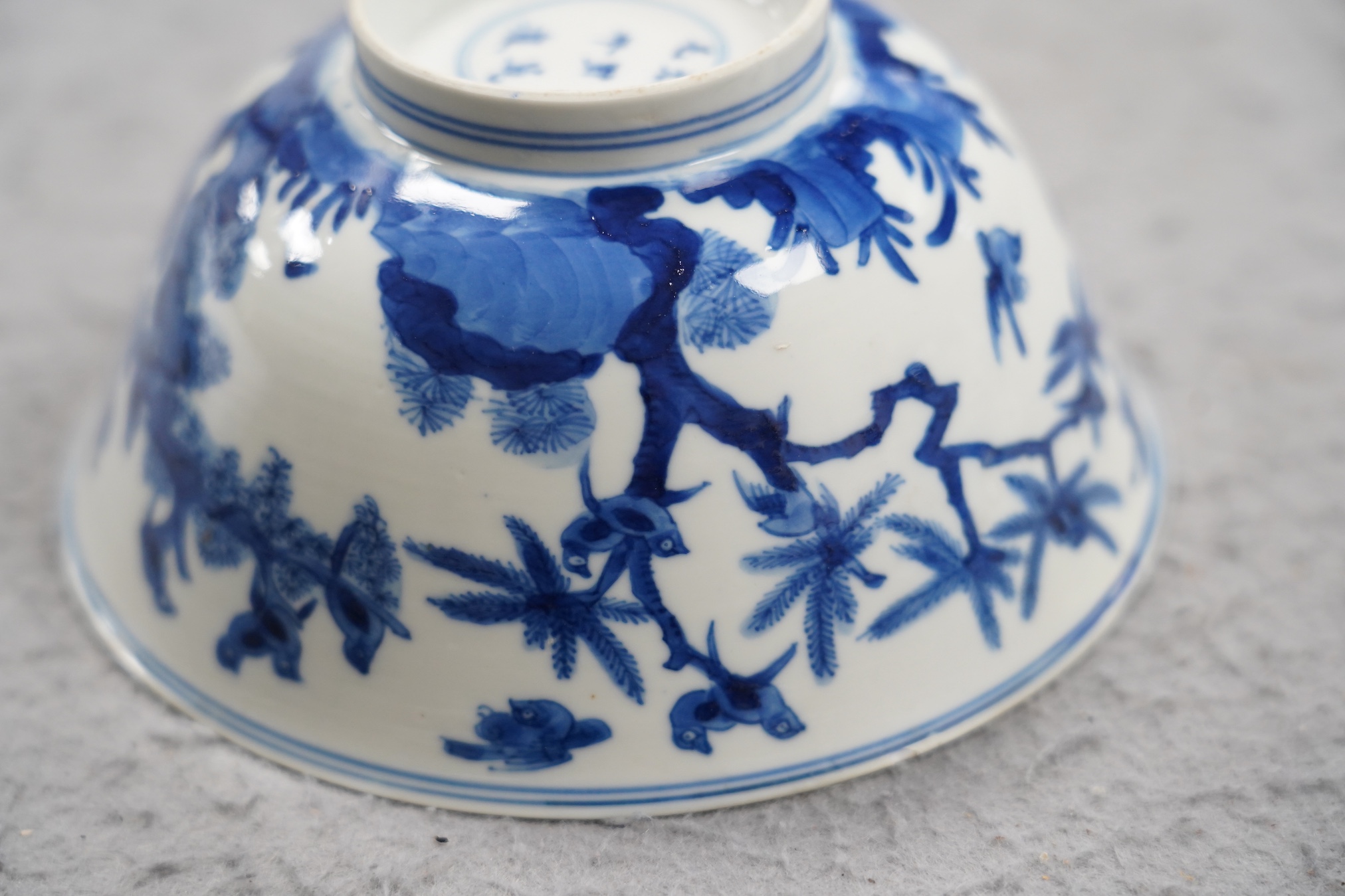 A near pair of Chinese blue and white ‘birds’ bowls, Kangxi period, one bowl restored
